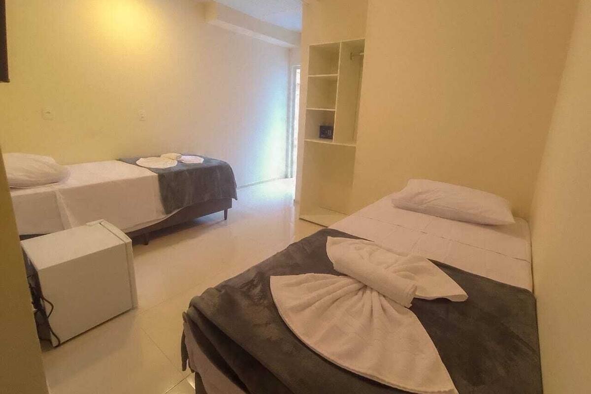 A hotel room with two single beds, a small desk, and a wardrobe.