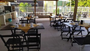 An outdoor café with multiple tables and chairs, some with yellow tablecloths. - Residencial Terrazas (Florianópolis)