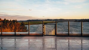 Vista desde un balcón sobre una masa de agua, con barandilla metálica y una escalera que baja hacia el agua.