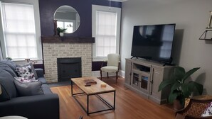 Un salon comprenant un canapé, une table basse, un téléviseur, une cheminée et un fauteuil.