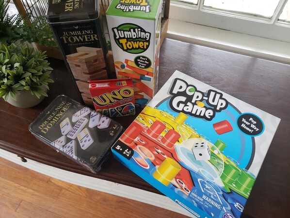 A variety of board games including JUMBLING TOWER, UNO, and POP-UP GAME on a wooden table. - The Moise Manor, a 1934 Bungalow, centrally located in the heart of Sumter. (Sumter)