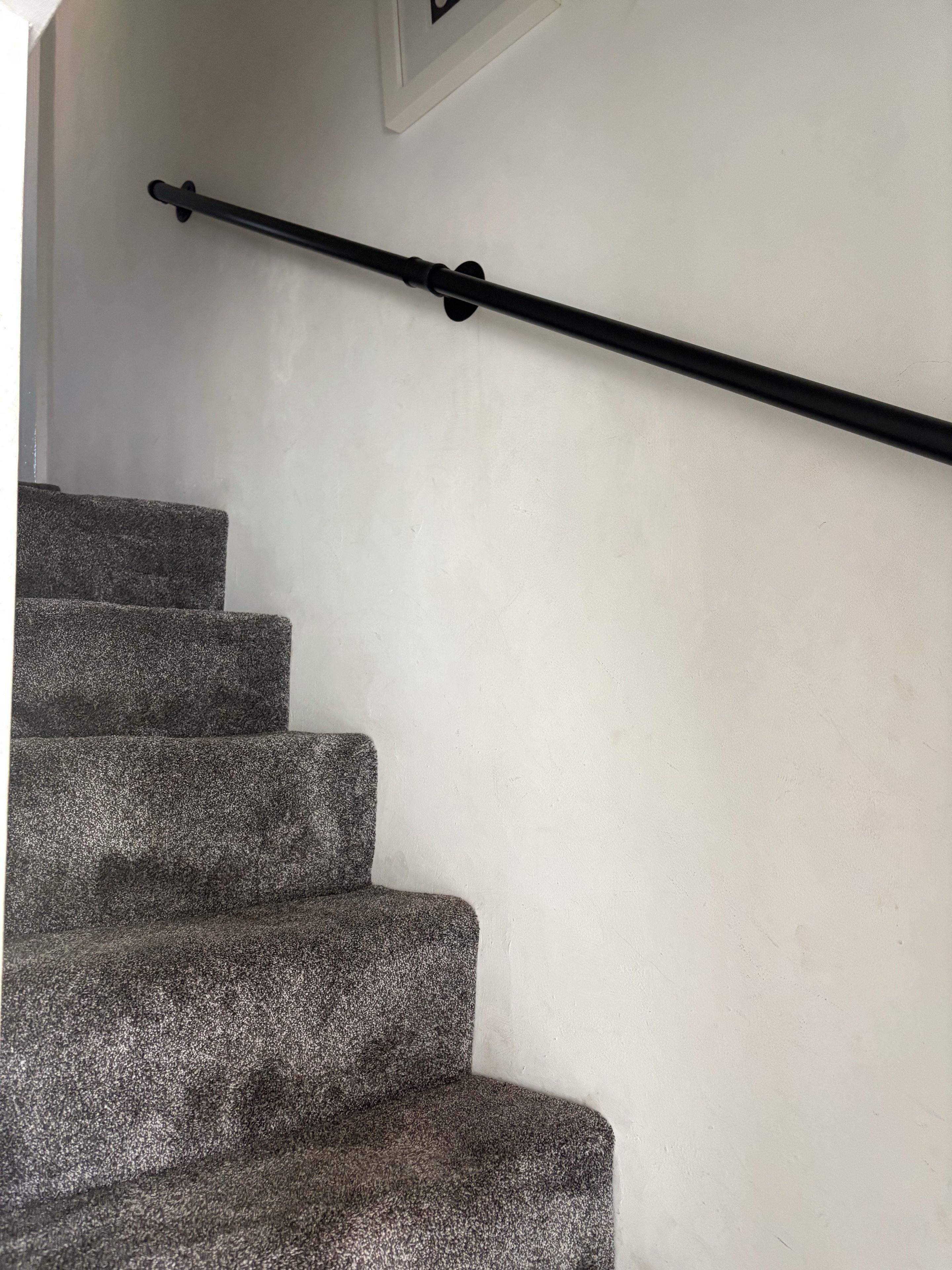 A staircase with a handrail and carpeted steps.