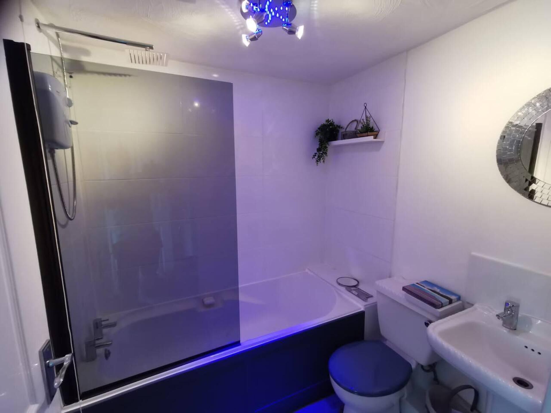 Un baño moderno con cabina de ducha de vidrio, un lavabo blanco y un inodoro.