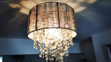 En ljuskrona med en cylindrisk lampskärm och kristallprydnader.