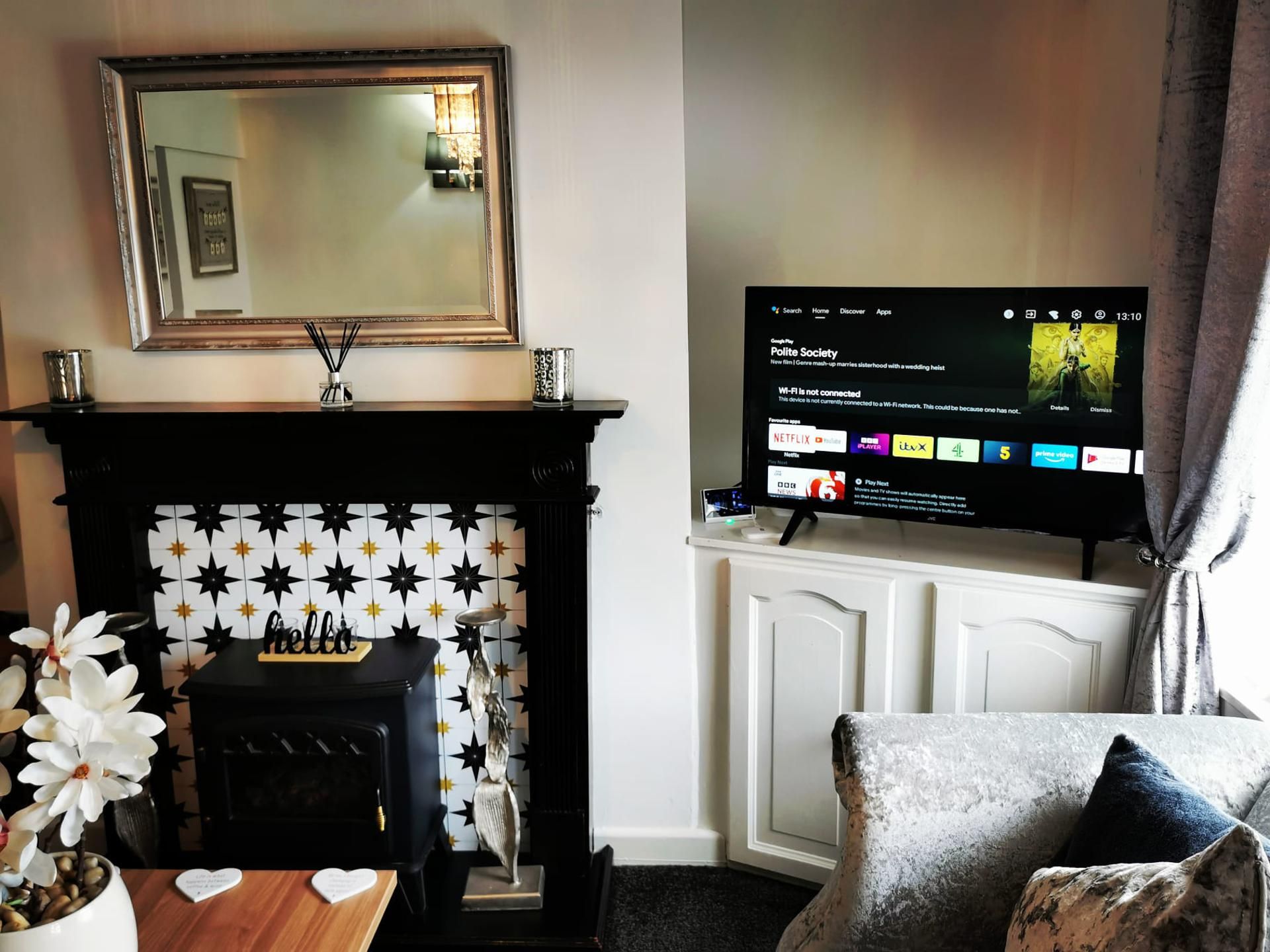 A living room with a fireplace, a television mounted on a cabinet, and a decorative mirror above the fireplace.