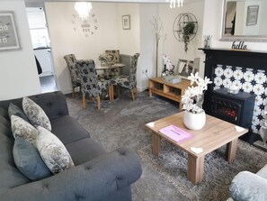A living room with a sofa, chairs, a coffee table, a fireplace, and a wall clock. - 2-bed House in Macclesfield Cheshire (Macclesfield)