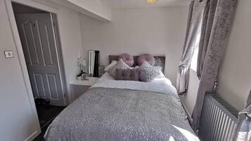 Une chambre à coucher avec un lit, une table de chevet, un miroir et un radiateur.