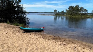 A sandy beach with a kayak and a calm lake.