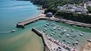 An aerial view of a coastal town with a marina, a lighthouse, and residential buildings. - Swn Y Mor - 1 Bedroom Studio - Saundersfoot (Saundersfoot)