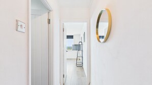 A hallway with a white door, a framed picture, and a gold-framed mirror on the wall. - Swn Y Mor - 1 Bedroom Studio - Saundersfoot (Saundersfoot)