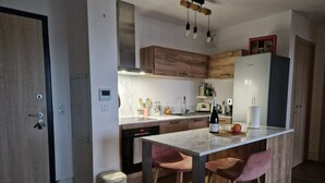 Een compacte keuken met een centraal eiland, houten kastjes en moderne apparatuur.