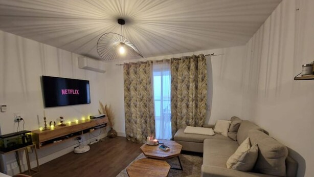Een woonkamer met een flatscreen televisie, een bank, een salontafel en een open haard.