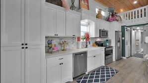 A modern kitchen with white cabinetry, stainless steel appliances, and a wooden ceiling. - Charming, quiet, sun filled, lakefront  (Willis)