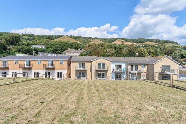 A row of townhouses with a grassy hill in the background.