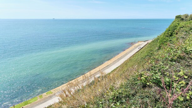 Eine Küstenstraße mit freiem Blick auf das Meer und einem entfernten Schiff.