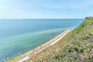 A coastal road with a clear view of the sea and a distant ship.