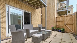 Eine Terrasse mit Korbmöbeln und Topfpflanzen.