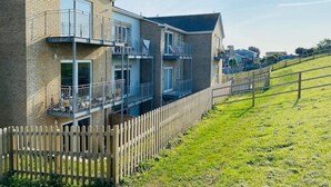 Un immeuble résidentiel à plusieurs étages, doté d’une façade en briques, de balcons et d’une clôture en bois.