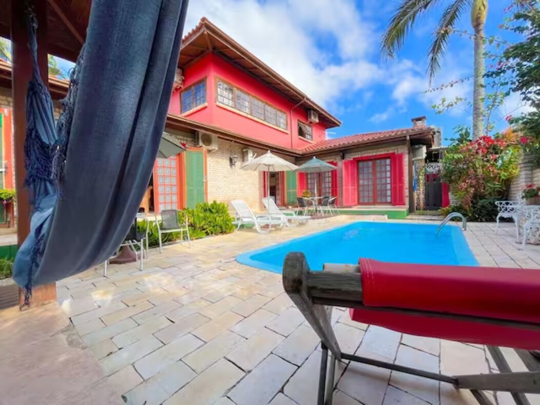 Zona junto a la piscina con una silla roja, una hamaca y una piscina.