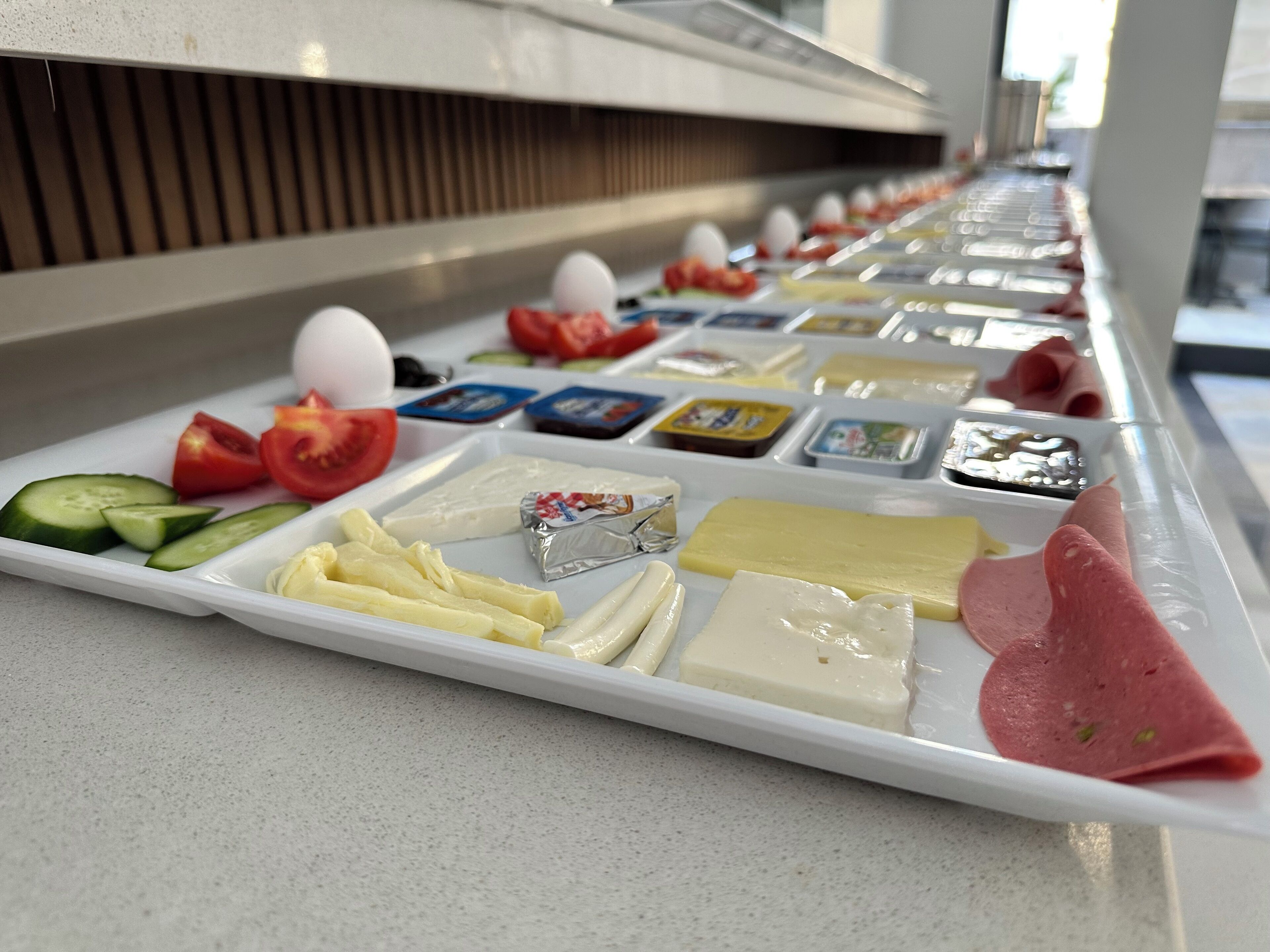 A buffet with various cheeses, meats, and vegetables.