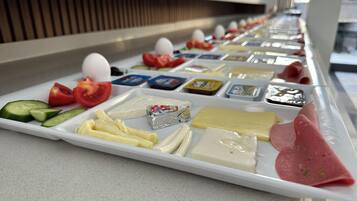 A buffet with various cheeses, meats, and vegetables.