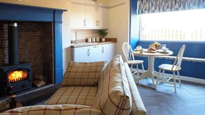 A cozy living room with a fireplace, a sofa, and a dining area with chairs and a table. - Welcome to our charming holiday cottage with breathtaking views of Whitby Abbey (North Yorkshire)