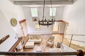 A spacious living area with a chandelier, a sofa set, and a staircase.