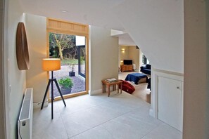 A room with a large window, a floor lamp, a small table, a sofa, and a television.