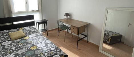 Et soveværelse med seng, skrivebord, stol og garderobeskab.