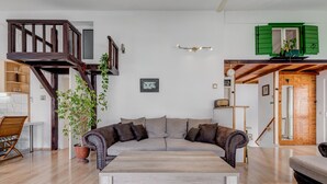 A living room with a wooden staircase, a sofa, a coffee table, and a potted plant. - Spacious Apartment w Three Balconies and Parking (Split)