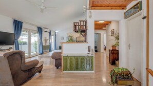 A spacious living area with a sofa, a television, a staircase, and a kitchen area. - Spacious Apartment w Three Balconies and Parking (Split)