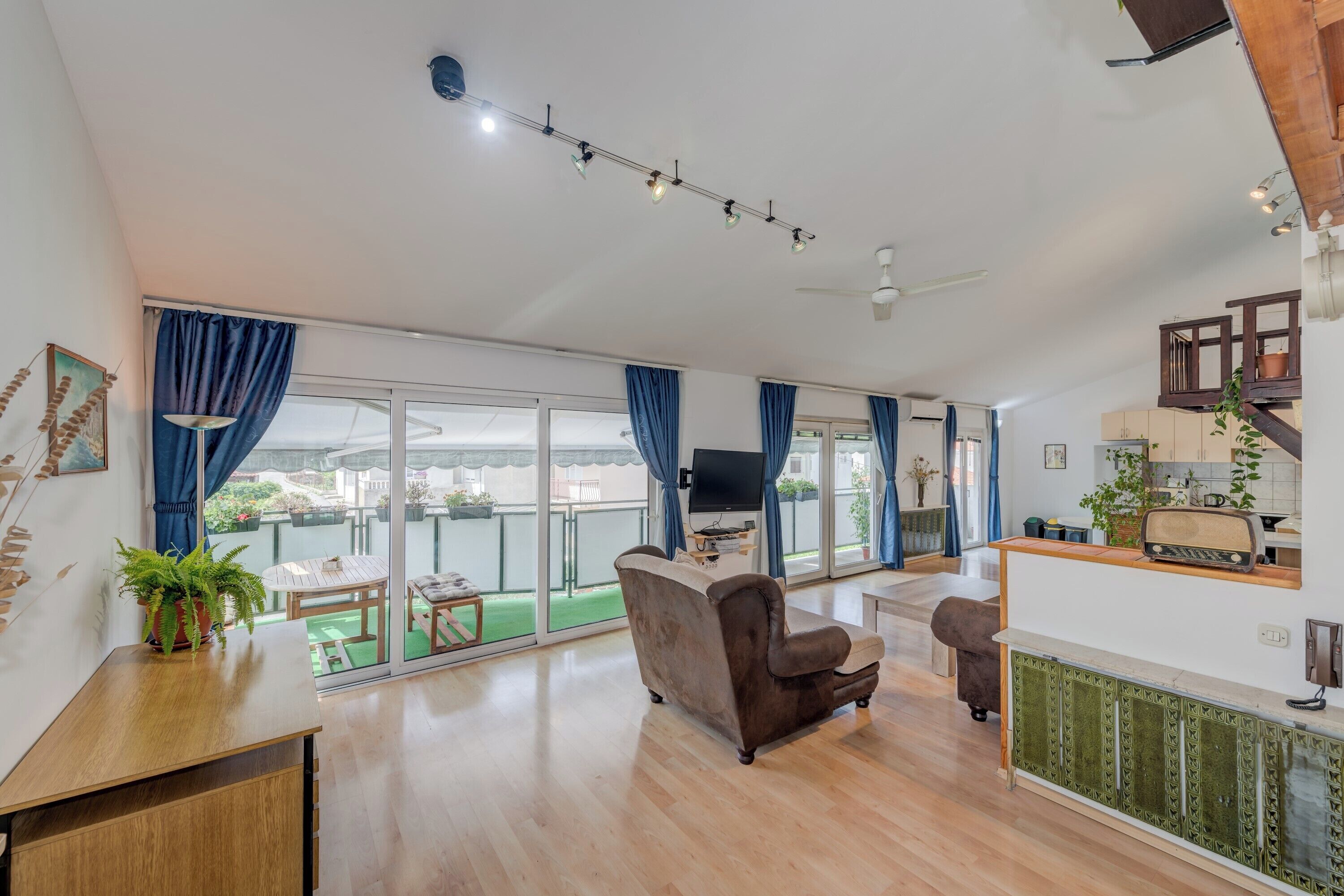 A spacious living area with a sofa, a dining table, and a kitchen area with a radio.