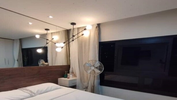 A modern hotel room with a large bed, a bedside table, a mirror, a ceiling fan, and a window with curtains. - Modern studio Rua Frei Caneca /Region Av Paulista (Consolação São Paulo)