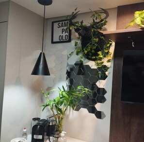 Eine moderne Küche mit einer sechseckigen schwarzen Spritzschutzwand, einer hängenden Pflanze, einer Kaffeemaschine und einem Schild mit der Aufschrift 'SAMPAOLO'.