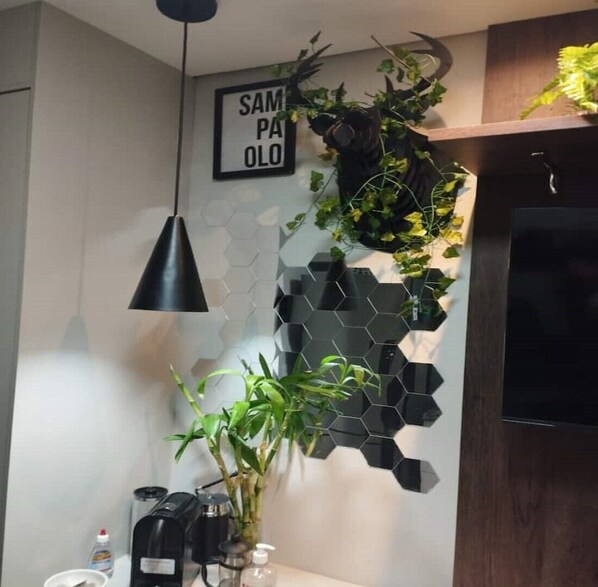 A modern kitchen with a hexagonal black backsplash, a hanging plant, a coffee machine, and a sign that reads "SAMPAOLO".