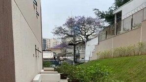 A narrow outdoor corridor with white cushioned seating and potted plants. - Modern studio Rua Frei Caneca /Region Av Paulista (Consolação São Paulo)