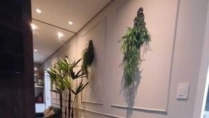 A modern living room with a green sofa, two patterned cushions, and a hanging plant. - Modern studio Rua Frei Caneca /Region Av Paulista (Consolação São Paulo)