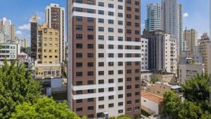 A high-rise building with a modern design, featuring a grid of windows and a mix of brown and white exterior panels. - Modern studio Rua Frei Caneca /Region Av Paulista (Consolação São Paulo)