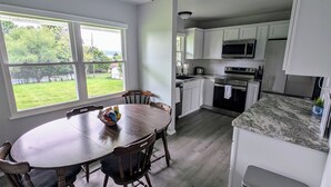 A modern kitchen with white cabinets, a granite countertop, and a dining area with a wooden table and chairs. - "Come Sail Away"
A charming place in Canandaigua designed with a sailing theme.  (Canandaigua)