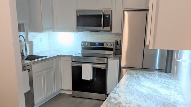 A kitchen with white cabinets, a stainless steel refrigerator, a microwave, an oven, and a sink. - "Come Sail Away"
A charming place in Canandaigua designed with a sailing theme.  (Canandaigua)