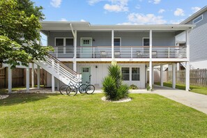 A two-story house with a covered porch, a staircase, and a small garden area with a tree and two bicycles. - WALK TO THE BEACH!!! Entire 5 bedroom home + game room & fenced in grilling area (Carolina Beach)
