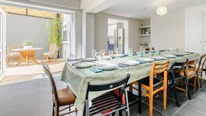 A dining area with a long table set for six, surrounded by chairs.