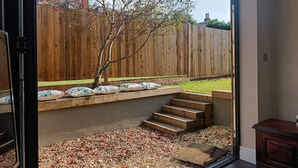 A view of a backyard with a wooden fence, a tree, and a set of stairs leading to a gravel area. - Great Value and Something Special (Margate)
