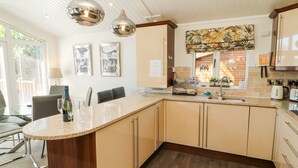A modern kitchen with a central island, pendant lighting, and a view of the dining area.
