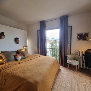 Restful retreat with a large bed, armchair, and wall-mounted mirror.