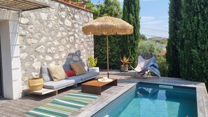 Relax by the pool surrounded by lush greenery and tall trees.