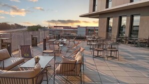 Un espace extérieur aménagé en terrasse, doté de différents types de sièges, notamment des canapés et des fauteuils, disposés sur un sol carrelé.