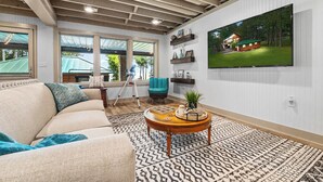 Un salon avec un canapé, une table basse et un grand téléviseur fixé au mur.
