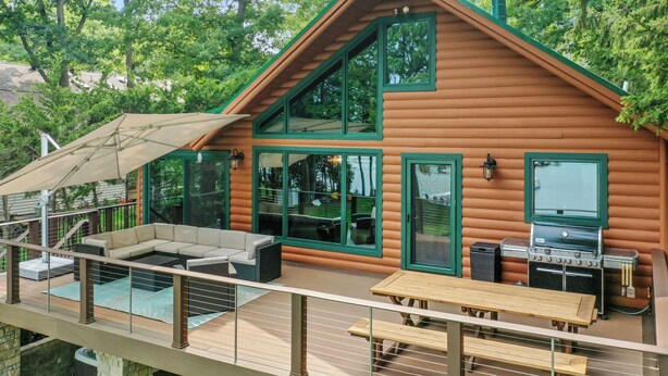 Une cabane en rondins dotée d’une terrasse, d’un espace salon extérieur et d’un barbecue.