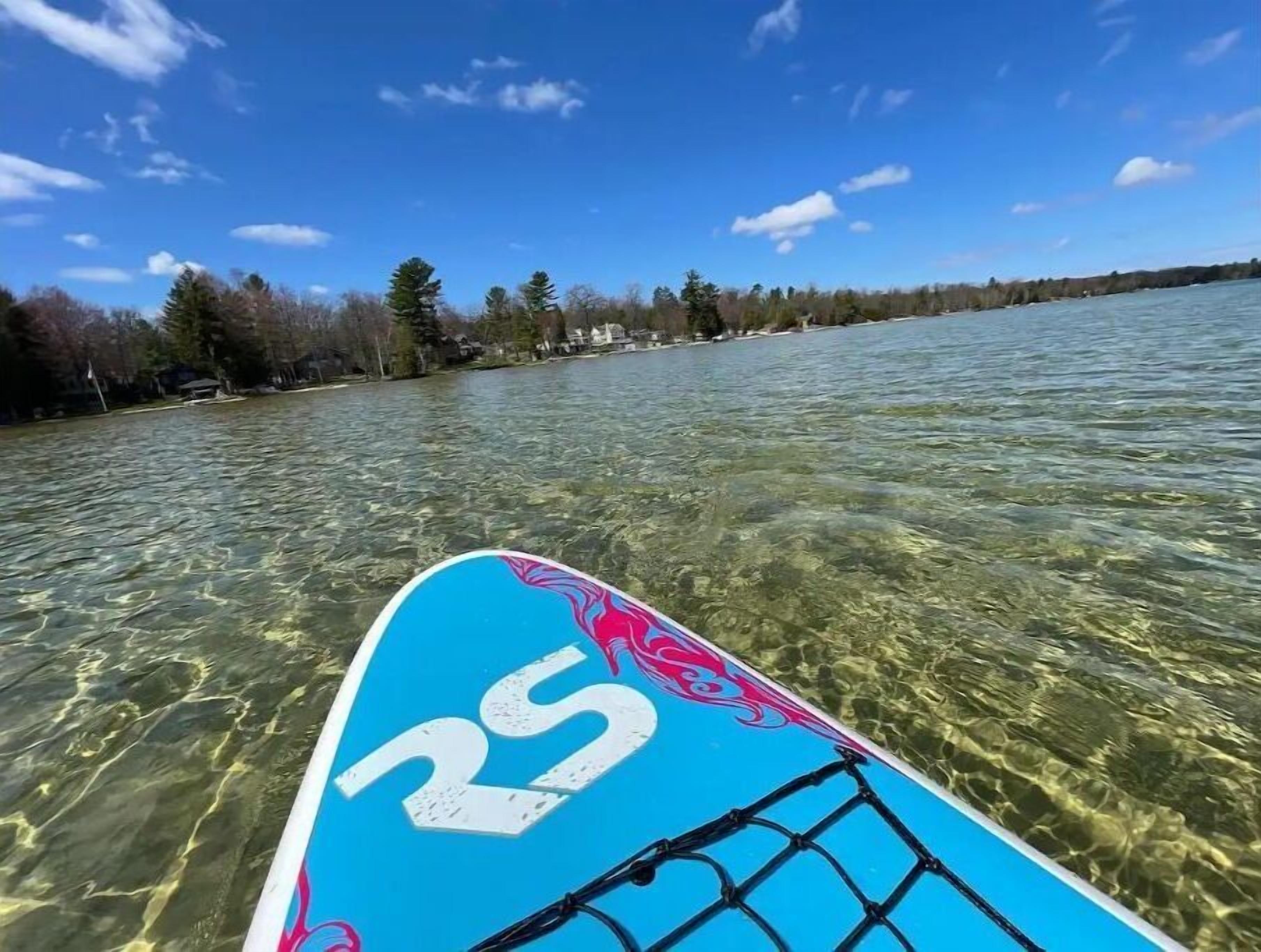 Ein ruhiger See mit einem Stand-Up-Paddleboard, erkennbar am Logo.